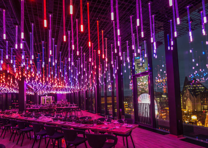 Restaurant Felix Leipzig Innenansicht mit lila und rot beleuchteter Decke, mehreren großen Tafeln & Blick aus dem Fenster