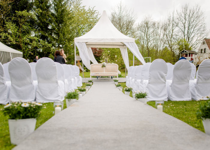Kleine Residenz Blick zum Platz für das Brautpaar unter einem Zelt mit weißen Stühlen und Bäumen im Hintergrund