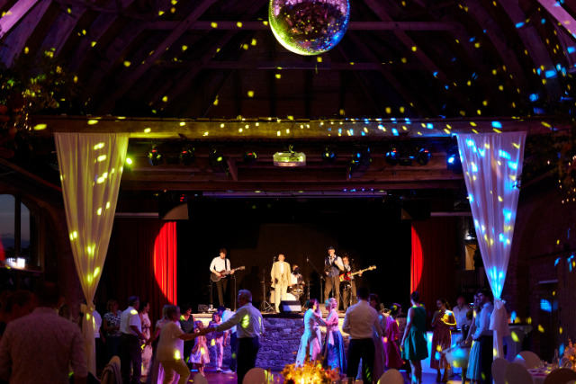 Blick auf die Bühne mit einer Band im Festsaal, Hocjhzeitsgäste tanzen bei dezenter Partybeleuchtung